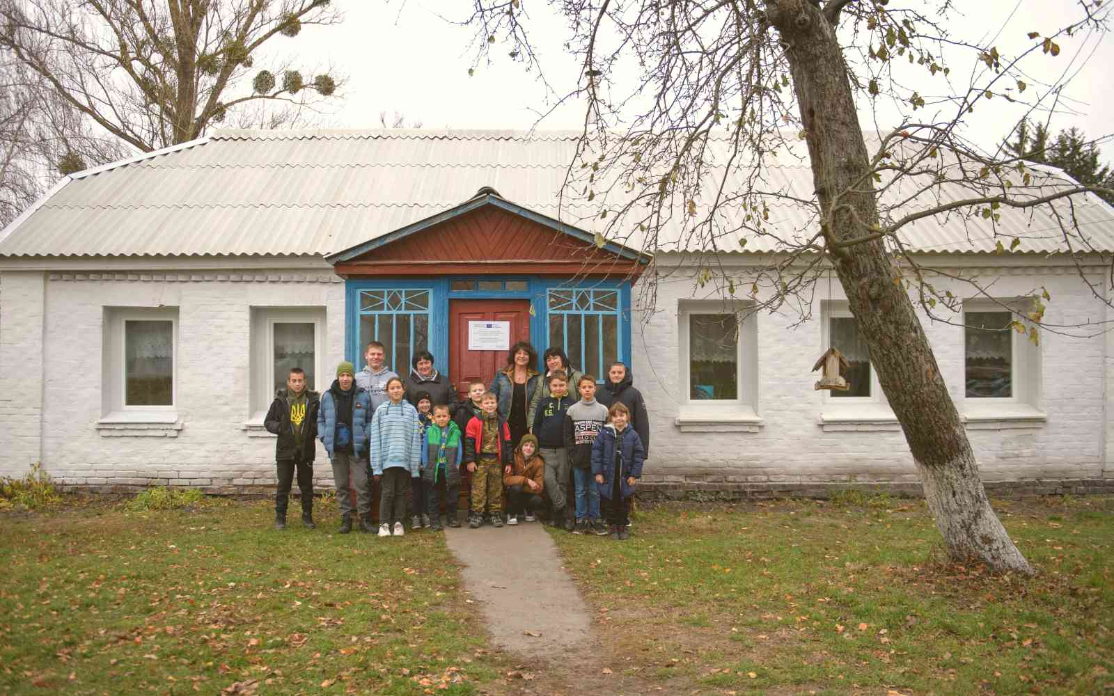 Students with their teacher standing in front of the renovated Pisky Secondary School. ©UNOPS/Veronika Yaresko
