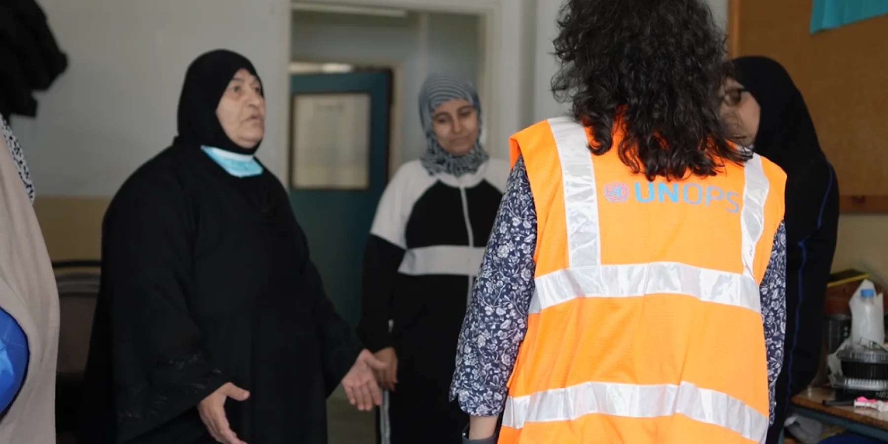 A UNOPS colleague speaks with women at Jaber Sabah Public School, currently serving as a shelter for displaced persons.