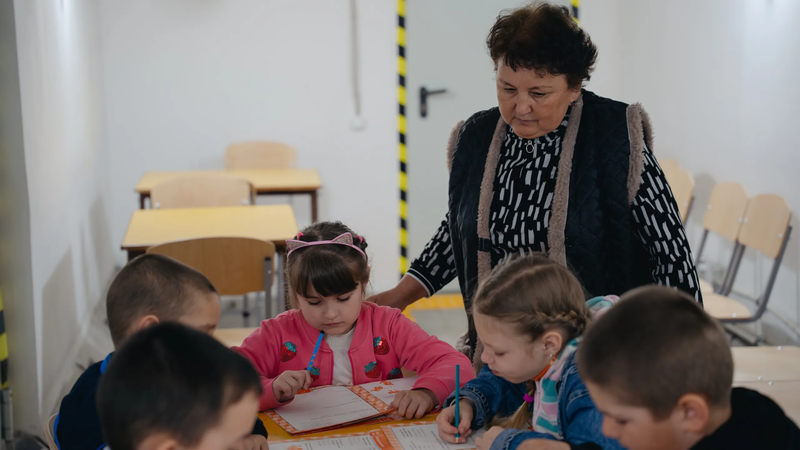Una profesora ayuda al alumnado que estudia en el refugio durante una alerta de ataque aéreo. ©UNOPS/Veronika Yaresko