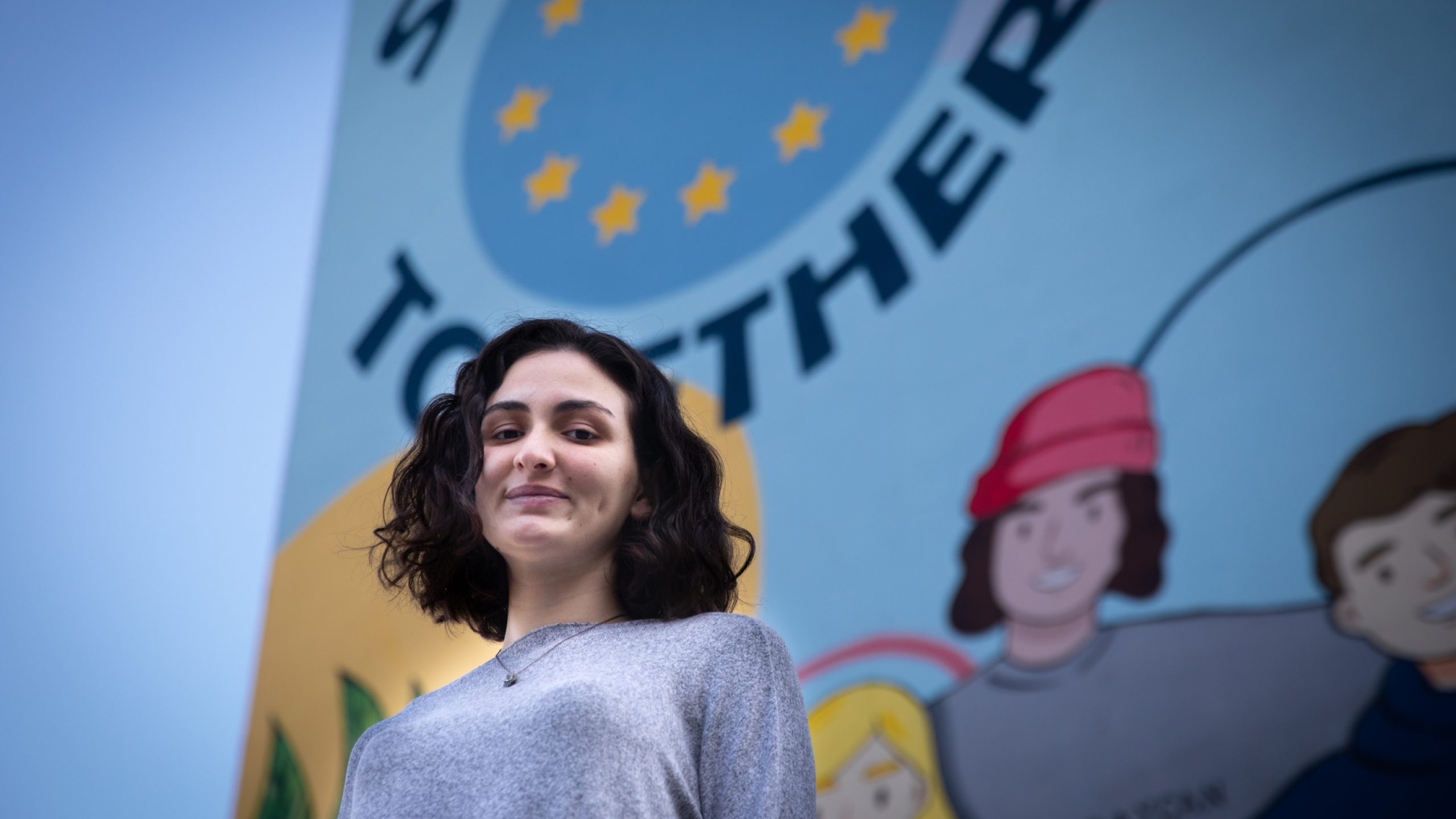 Derrière Nini Kutateladze, de Géorgie, une peinture sur le mur de la résidence étudiante porte l’inscription « L’union fait la force », qui est le thème du Partenariat oriental.