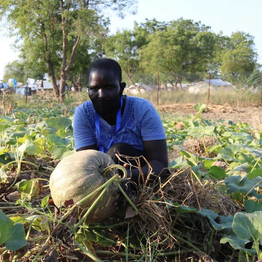 Rebecca Achok Deng prend la pose avec une courge de son potager, dans le village de Malou South.