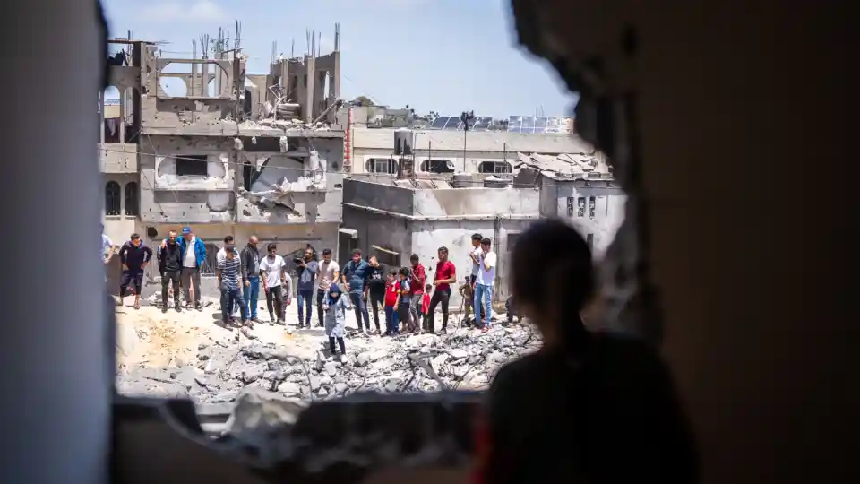 Varias personas observan los daños ocasionados en una zona residencial, Franja de Gaza. ©OMS