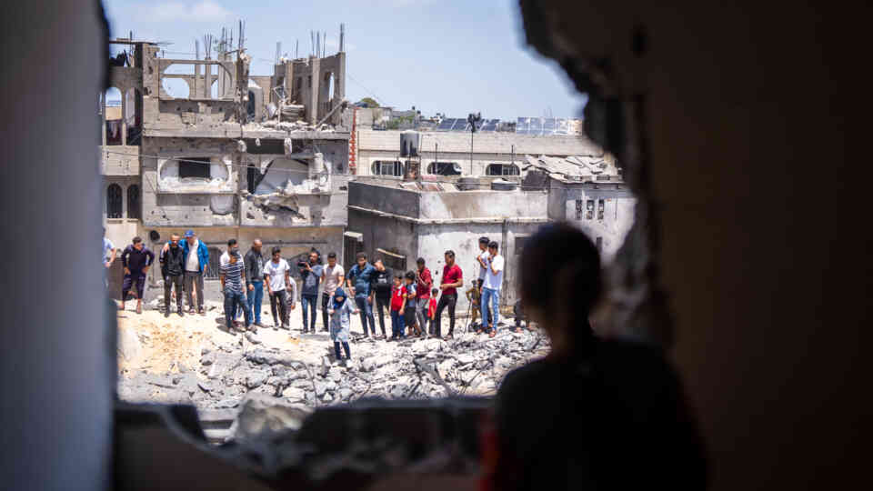 Varias personas observan los daños ocasionados en una zona residencial, Franja de Gaza. ©OMS