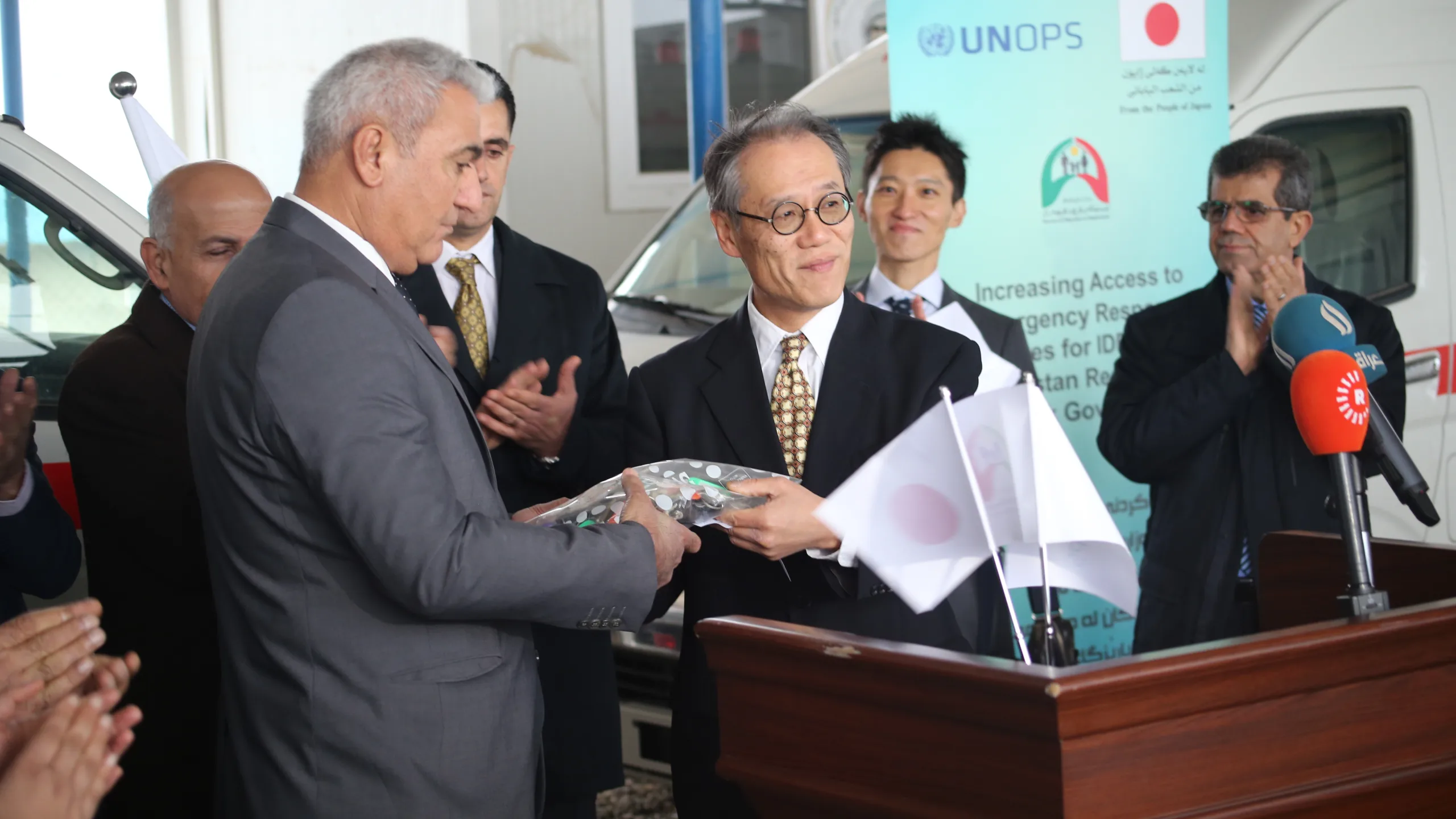 El Sr. Shokr Yaseen, Director General de la Oficina de Migración y Desplazamientos, recibe las llaves de las ambulancias de manos del Excmo. Sr. Fumio Iwai, Embajador de Japón en Iraq. ​