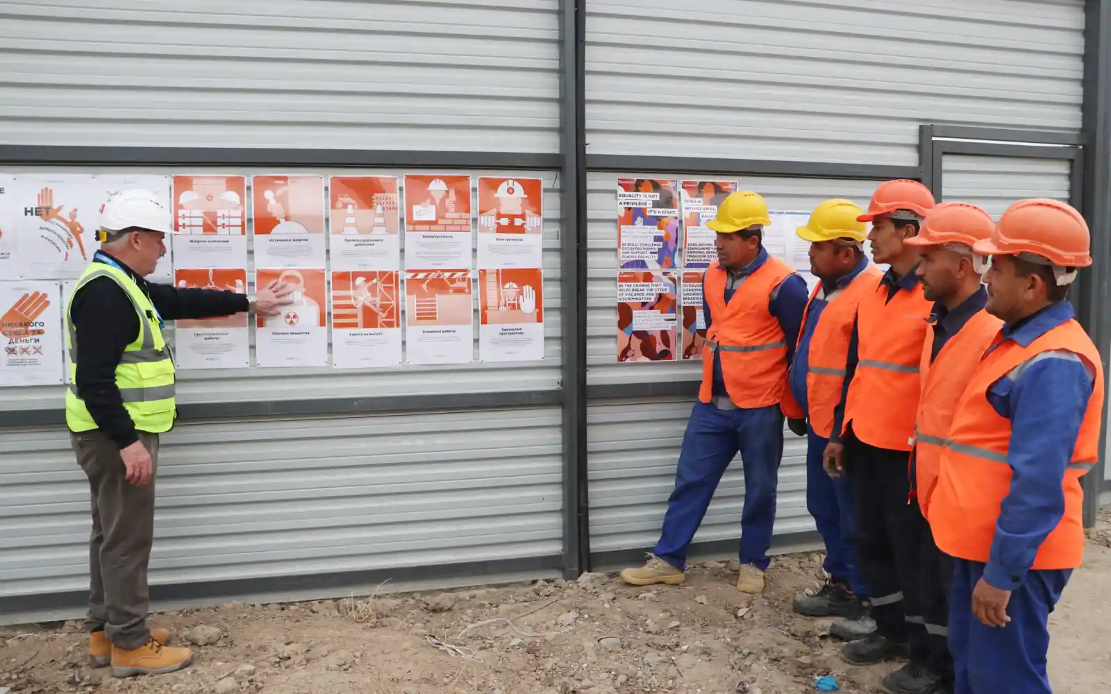 Construction site workers follow a safety briefing as a UNOPS instructor highlights key safety protocols to ensure compliance and hazard prevention.