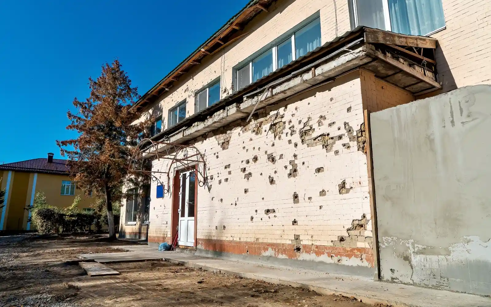 Before: The preschool's facade after a missile strike, showing shrapnel damage on the walls.