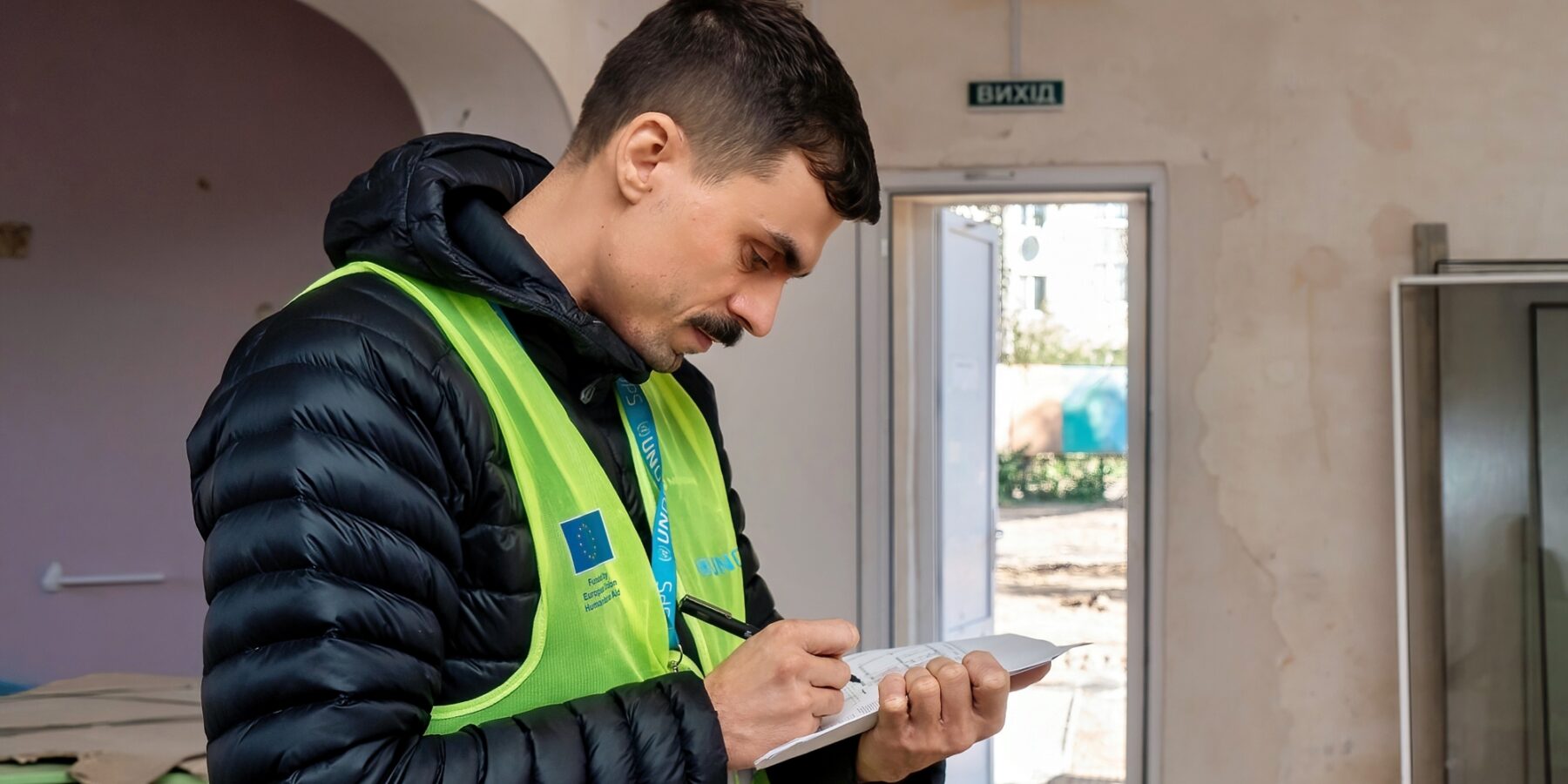Un ingeniero de UNOPS evalúa y documenta los daños estructurales en el interior del edificio.