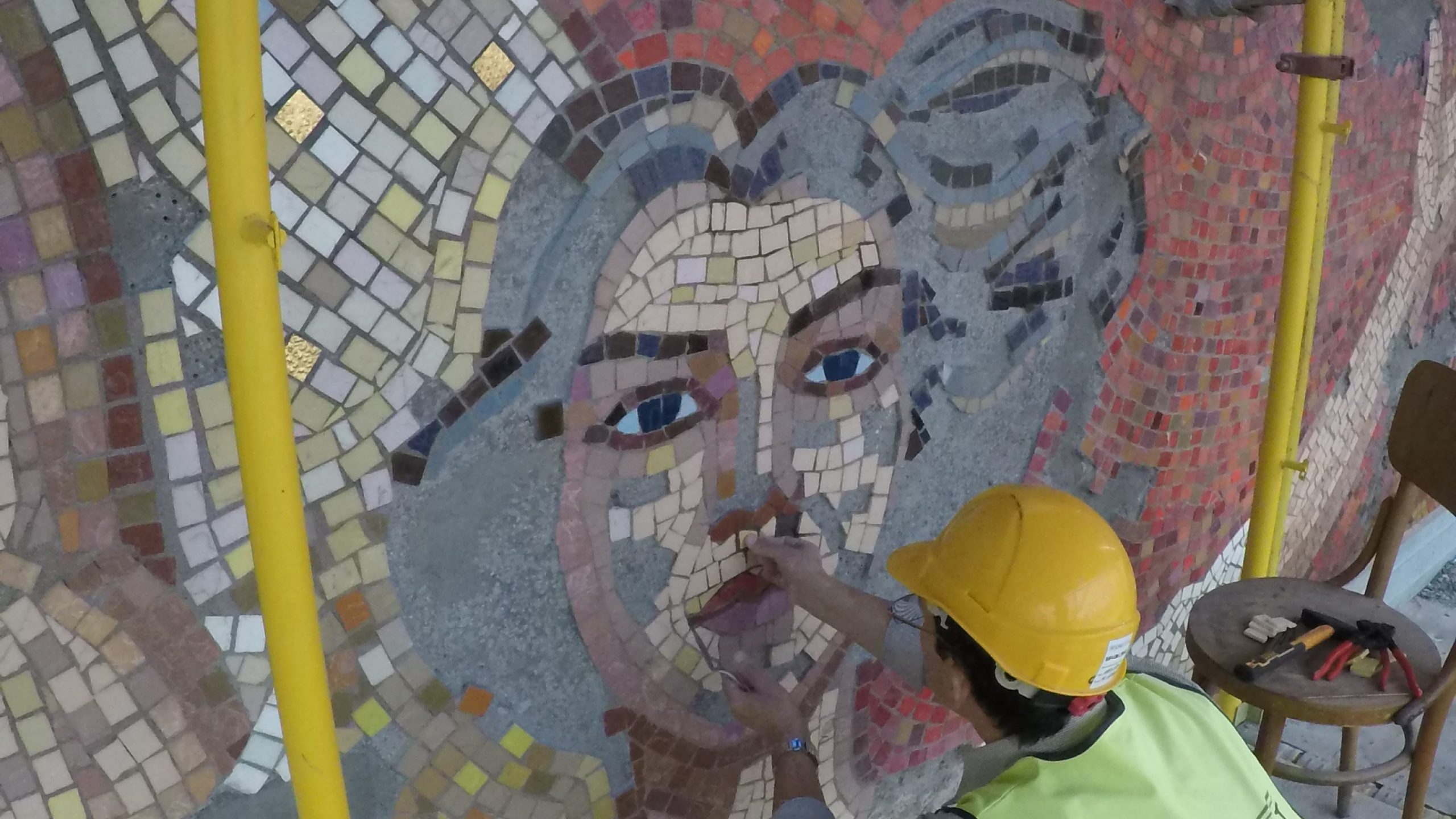 An expert examines the the remaining intact pieces mosaic.