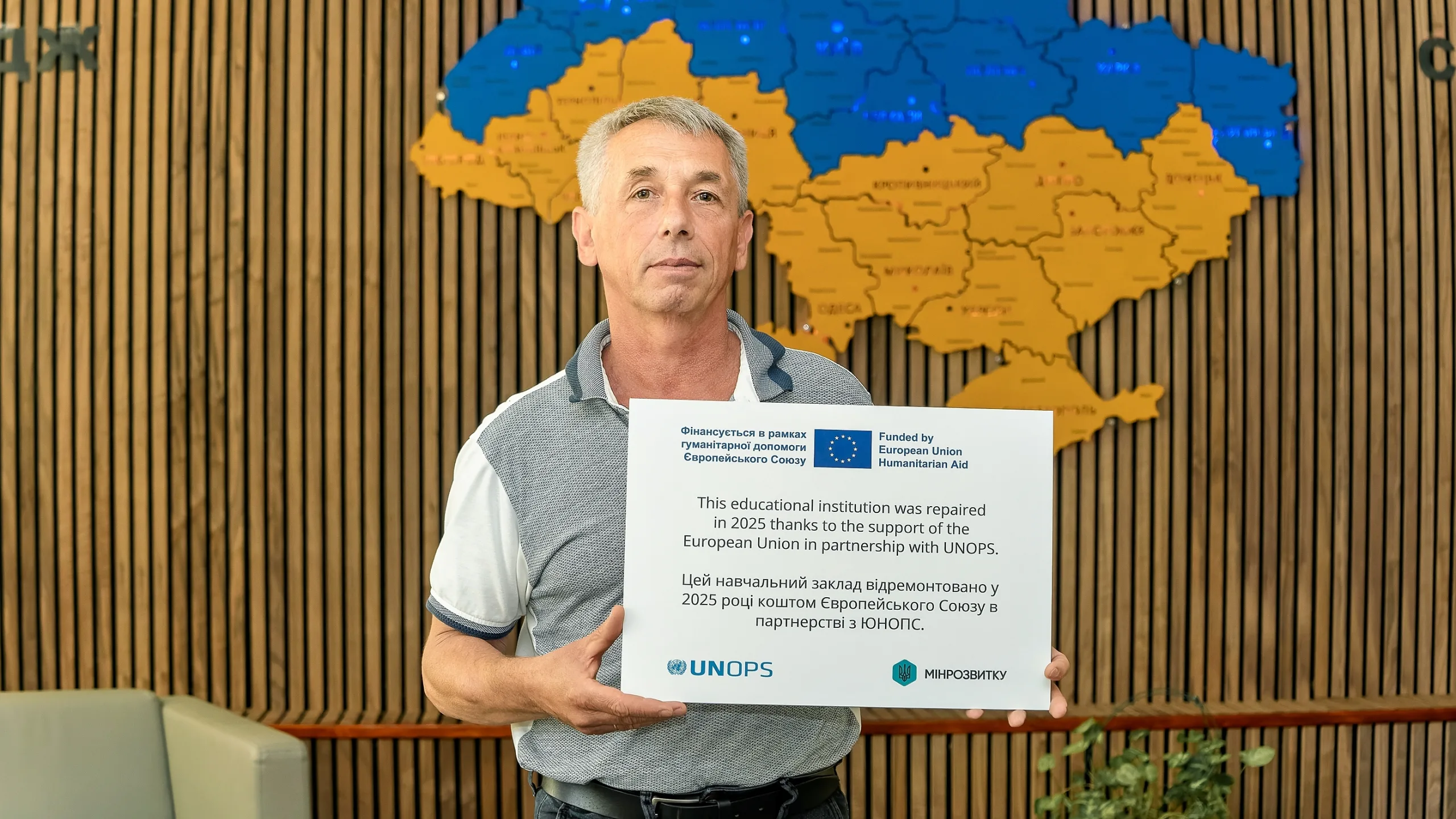 Yurii Aleksandrov, Senior instructor of the Mechanization and Transport Department, holds a commemorative plaque presented to the college after the repair works were completed. The plaque acknowledges the support of the European Union and UNOPS in the 2025 repairs.