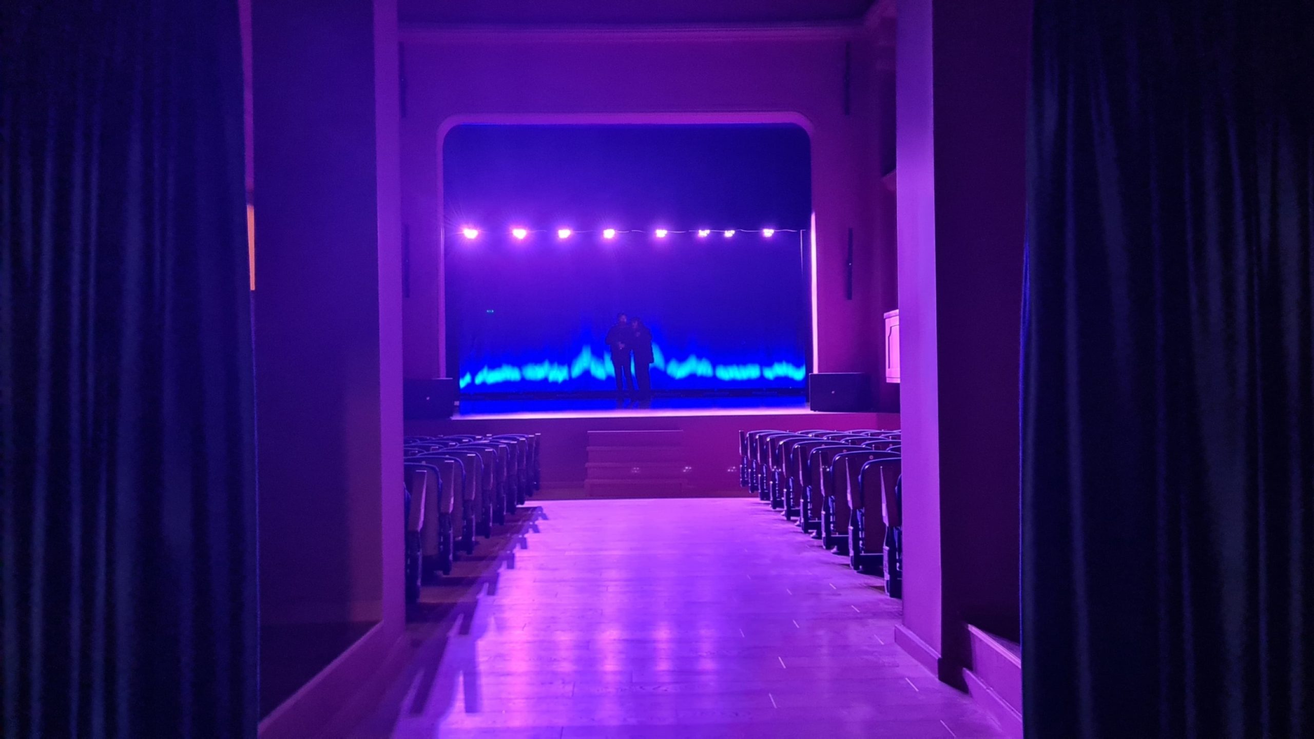 El auditorio restaurado del Teatro Nacional de Marionetas de Tirana, con un escenario vibrante y asientos modernizados, listo para recibir al público.
