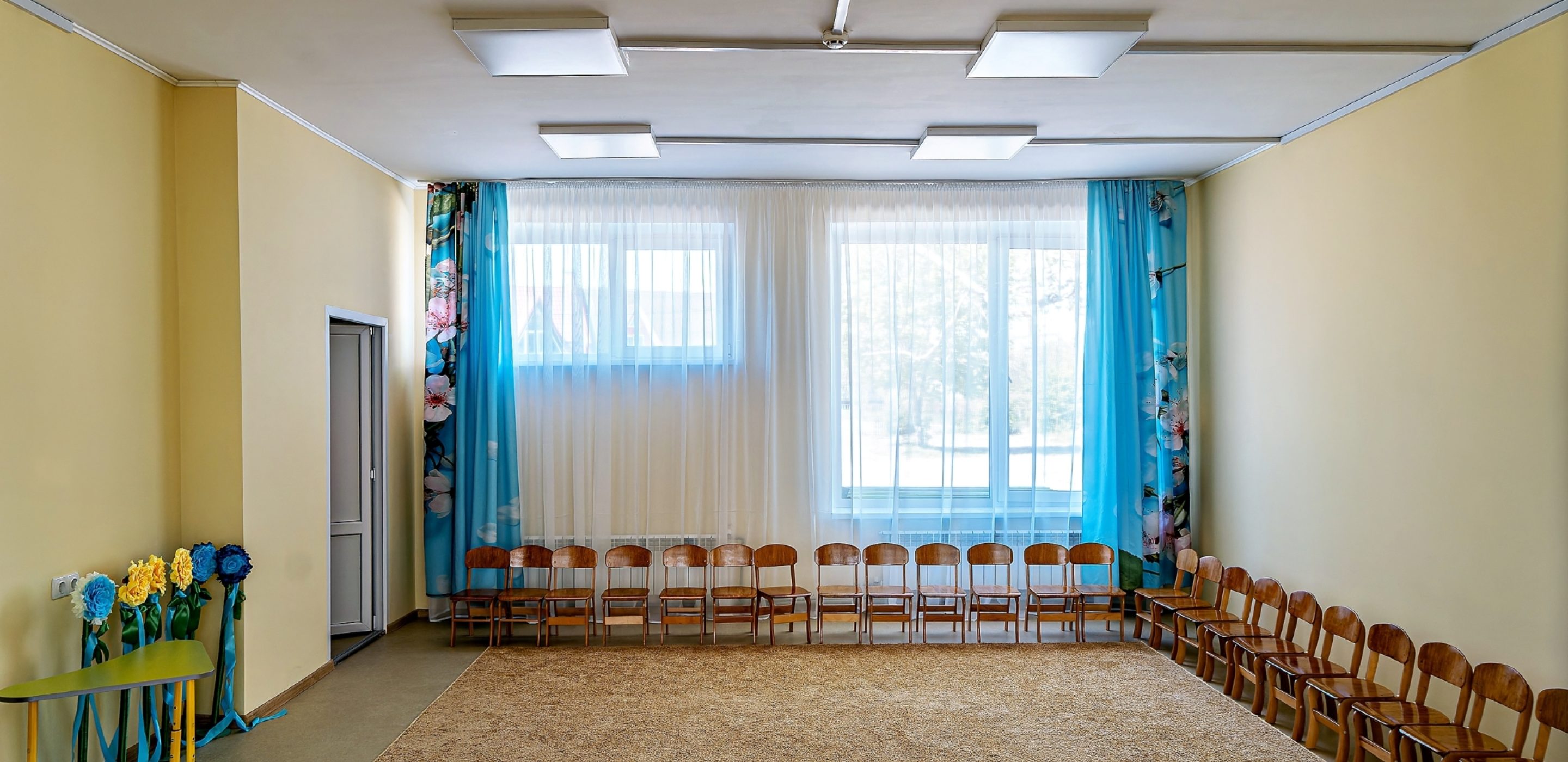 El salón de actos, recién reparado, con el suelo limpio, iluminación brillante y ordenadas filas de sillas, está listo para actos escolares, representaciones y reuniones.