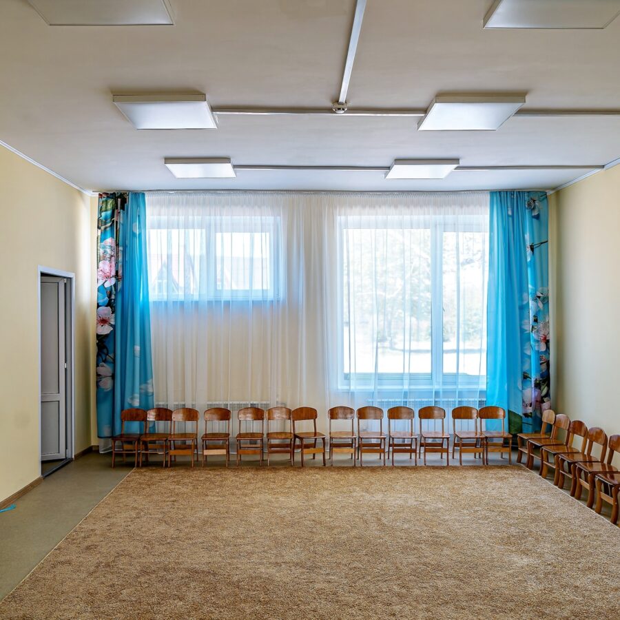 El salón de actos, recién reparado, con el suelo limpio, iluminación brillante y ordenadas filas de sillas, está listo para actos escolares, representaciones y reuniones.