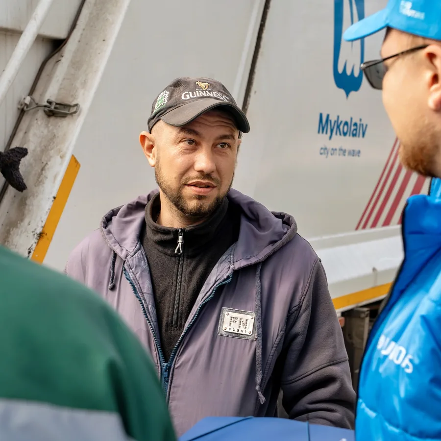 Un trabajador municipal de Mykolaivkomuntrans habla con un representante de UNOPS junto a un vehículo de recogida de desechos recién entregado.