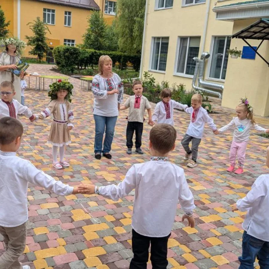 Children and teachers dance in a circle in the newly paved courtyard, celebrating their return to school.