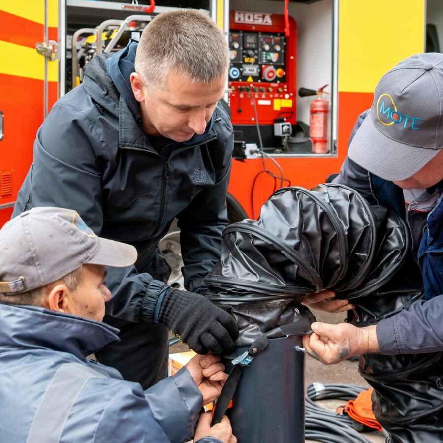 Des membres du personnel de Mykolaiv-obl-teplo-energo s’entraînent à déployer un tuyau à haute pression, servant à rediriger l’écoulement de l’eau pour permettre des réparations.